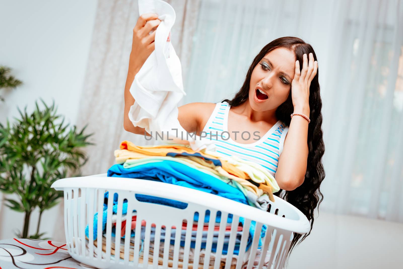 Bored young woman with basket laundry for ironing.