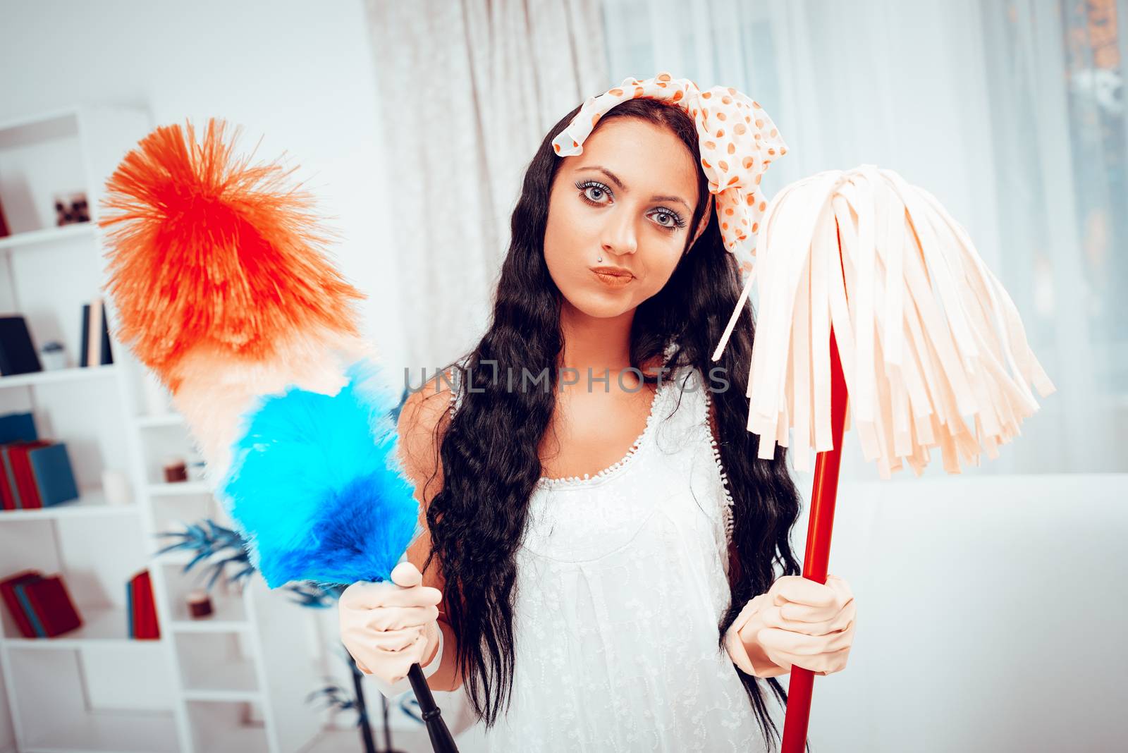 Portrait of a bored young housewife holding a cleaning equipment. Looking at camera.