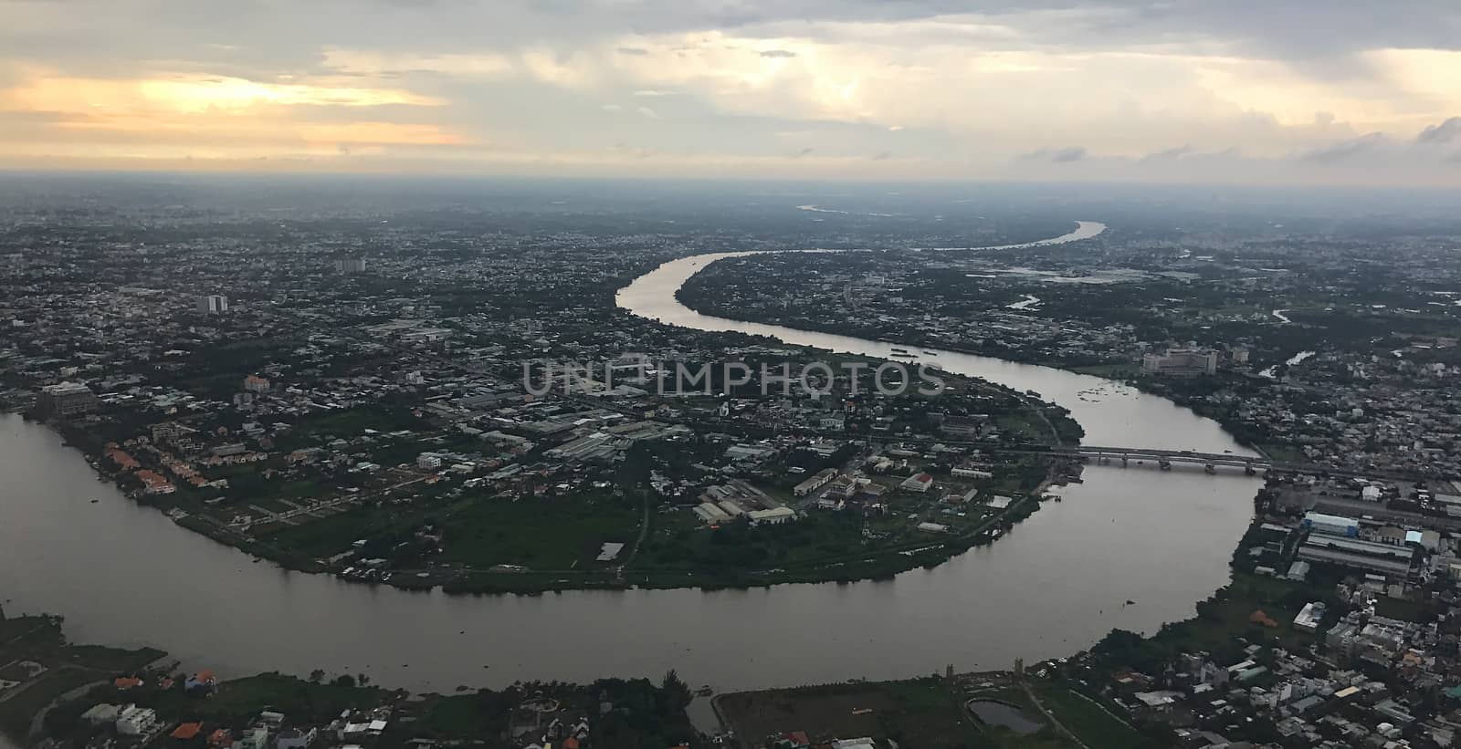Bird eye view from plane window: Ho Chi Minh City with meandering Saigon River at dusk on a rainy day
