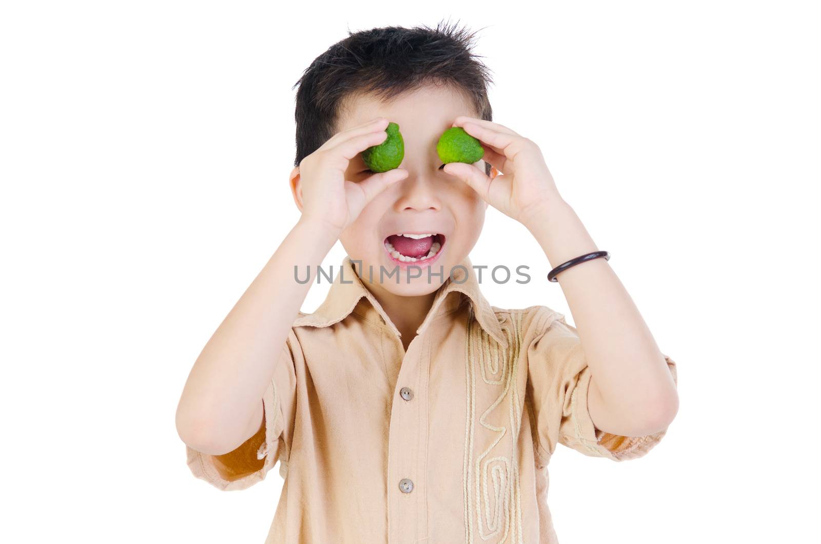 Happy adorable boy holding lemon  that cover both eyes while standing in front of white background