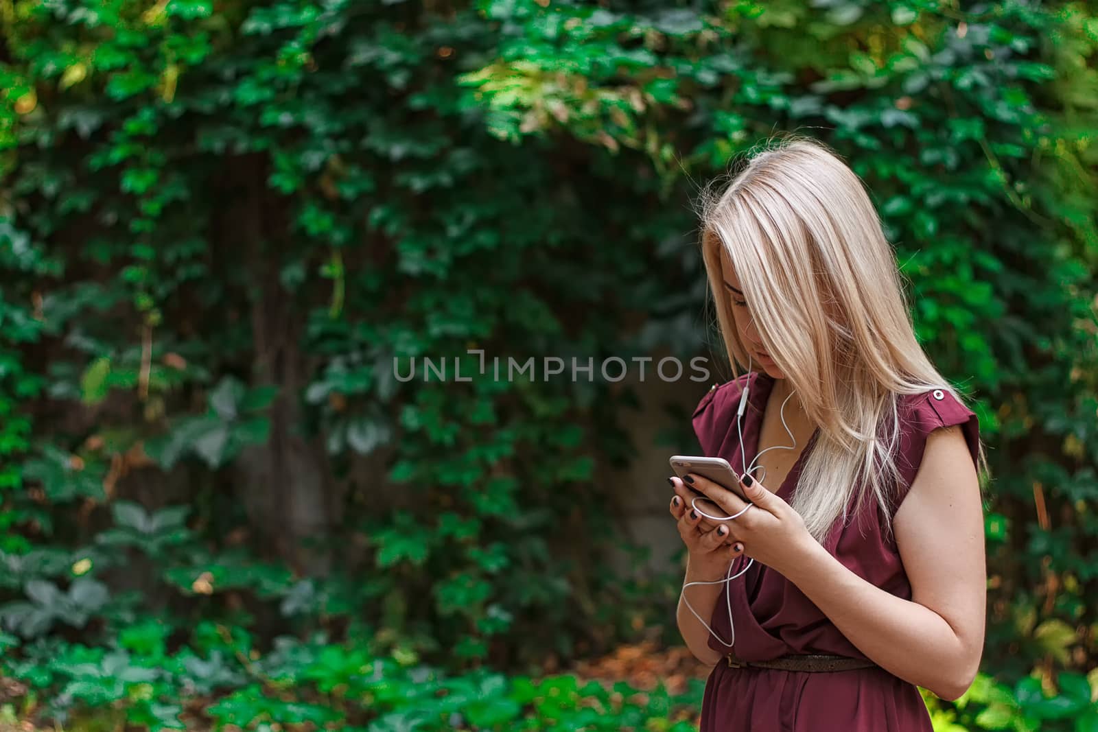 Young attractive woman at the park, she is texting with her smartphone