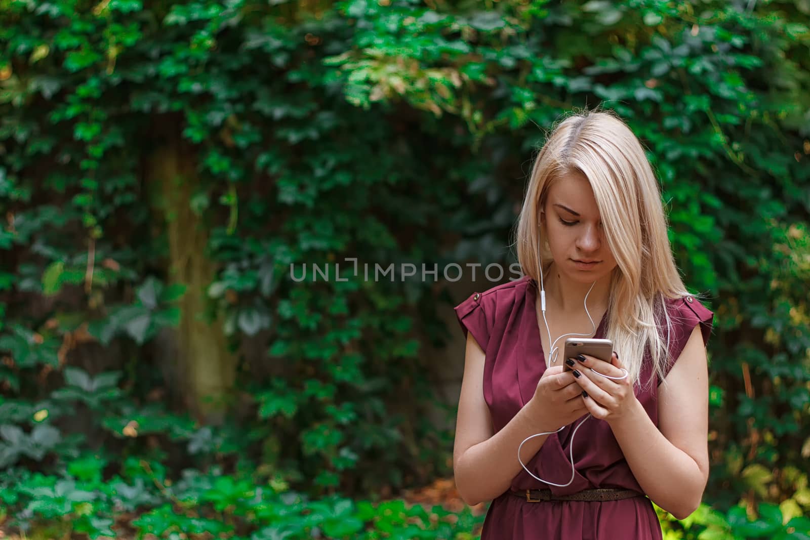 Young attractive woman at the park, she is texting with her smartphone