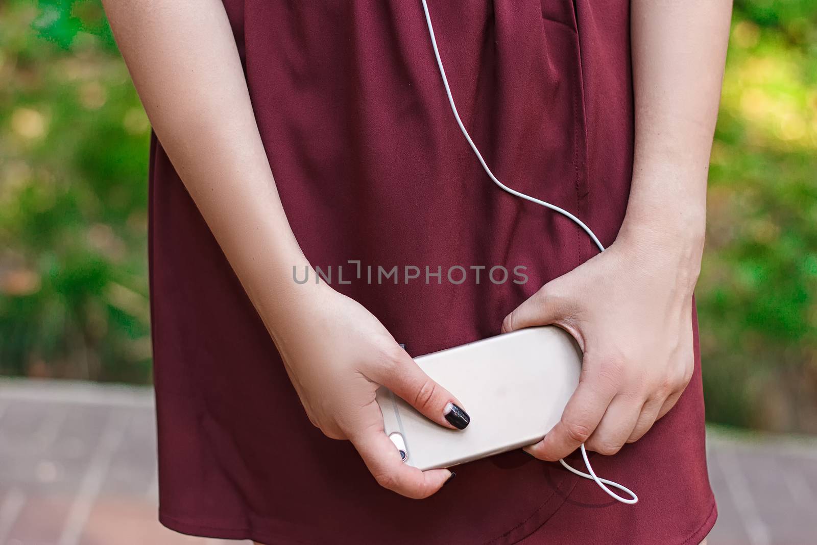 Smart phone in female hands. Girl typing on mobile phone in summer park