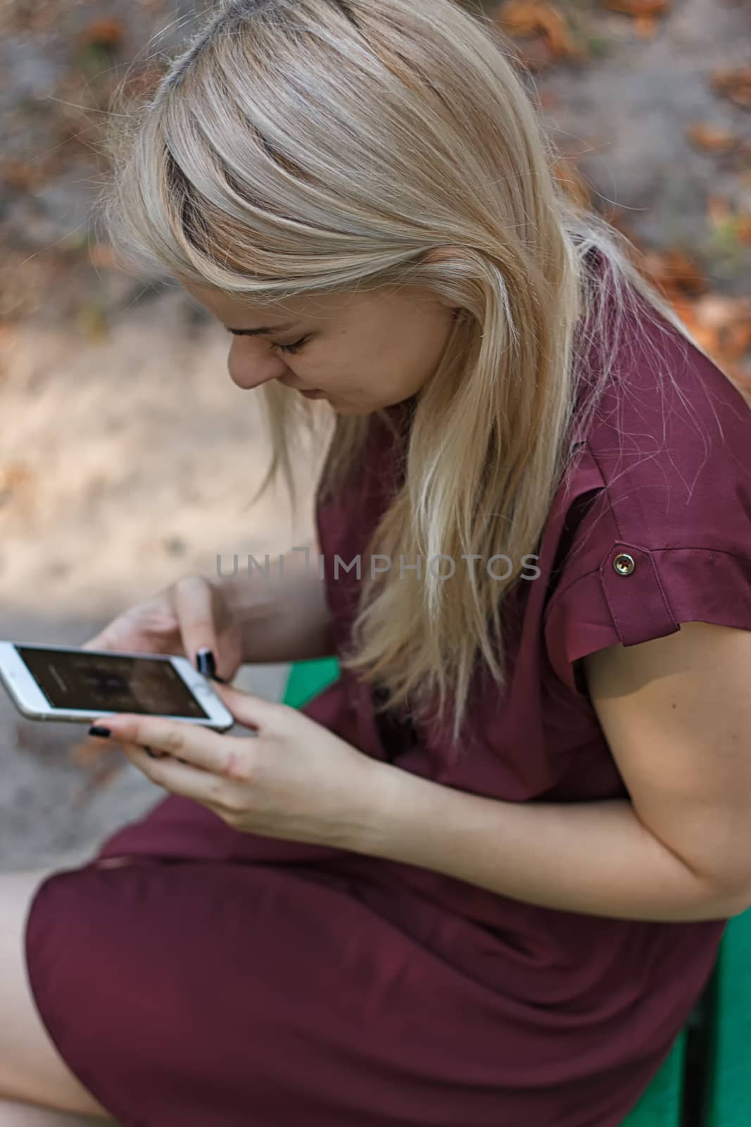 Young attractive woman at the park, she is texting with her smartphone