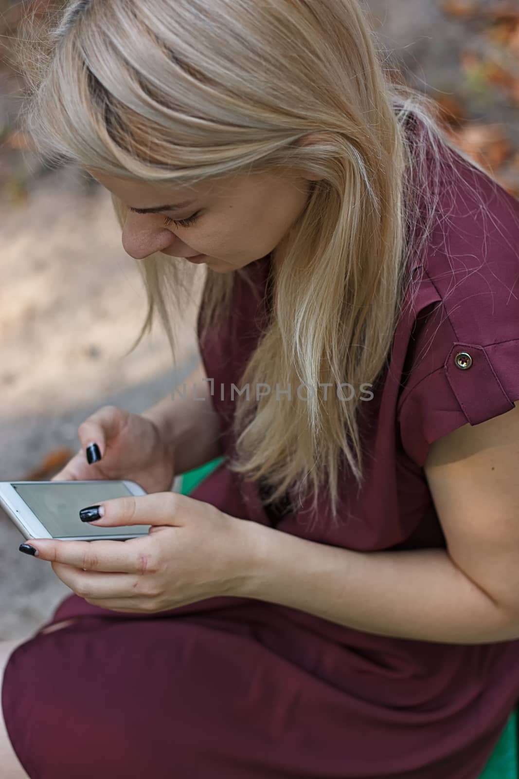 Young attractive woman at the park, she is texting with her smartphone