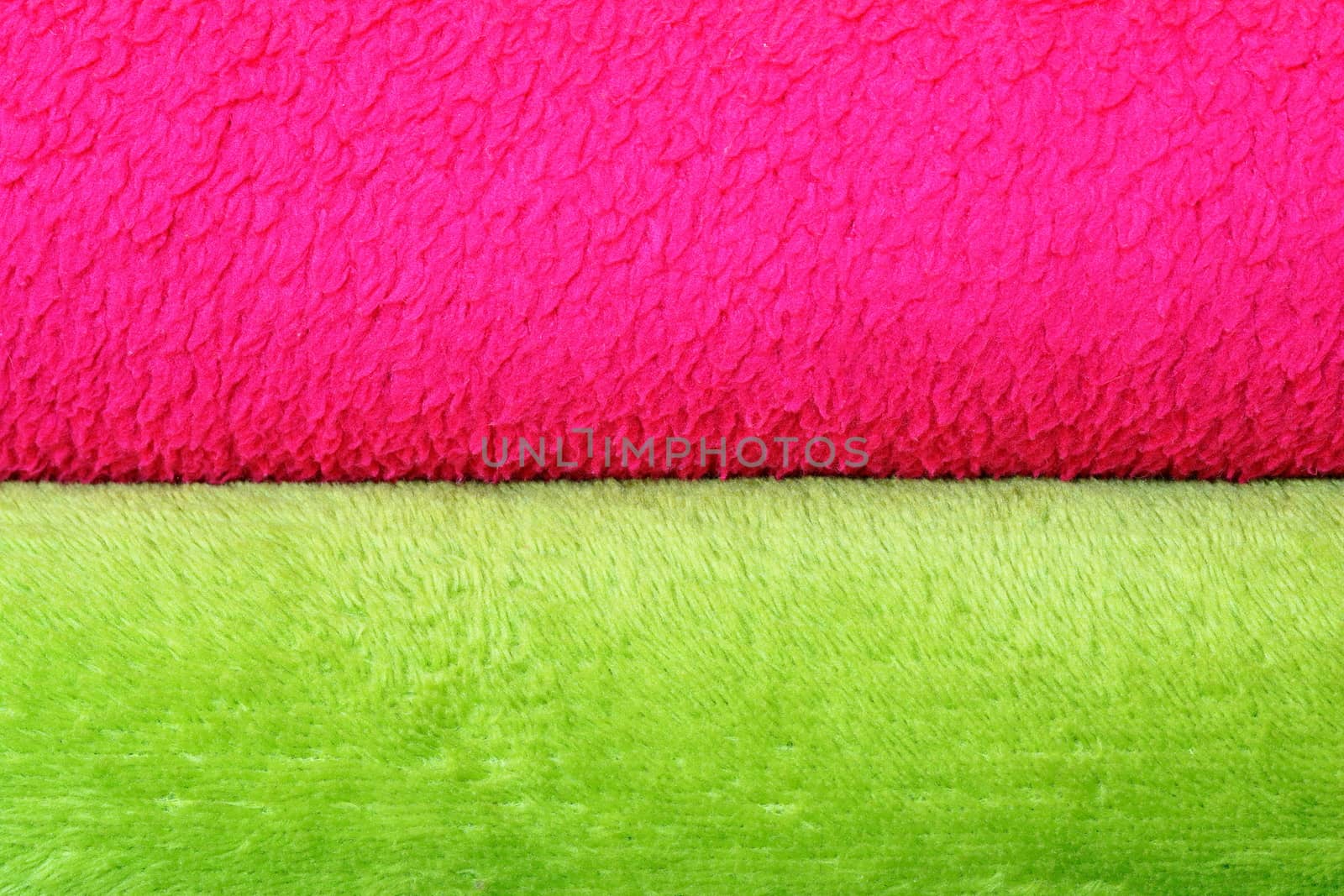 colorful background of textured blankets, detail of stack with green and pink material