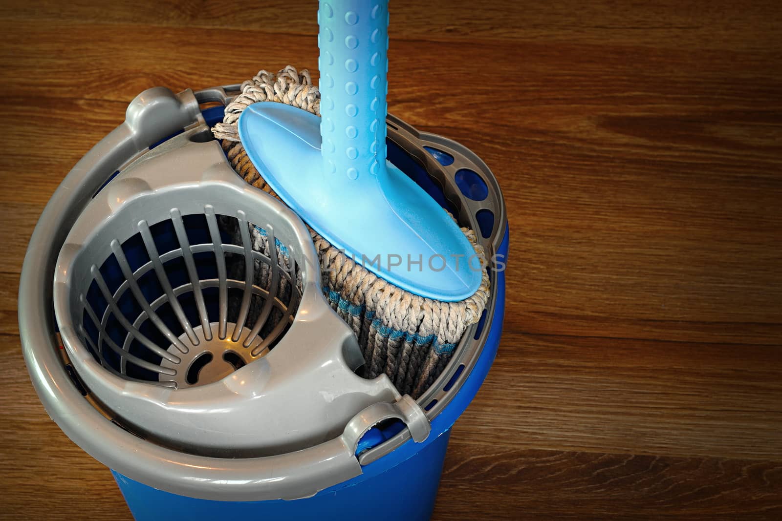 mop and blue bucket ready for cleaning wooden parquet floor