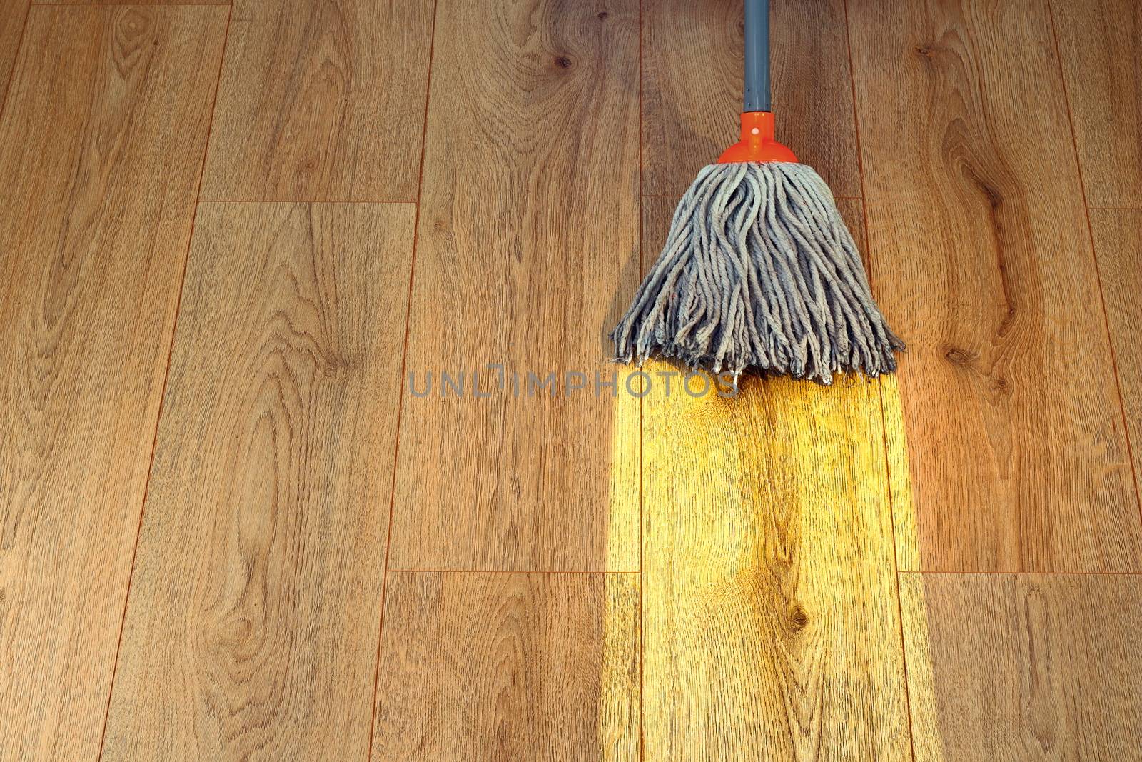 cleaning wooden floor with a mop by taviphoto