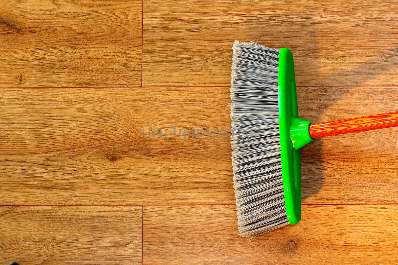 cleaning wooden floor with broom by taviphoto