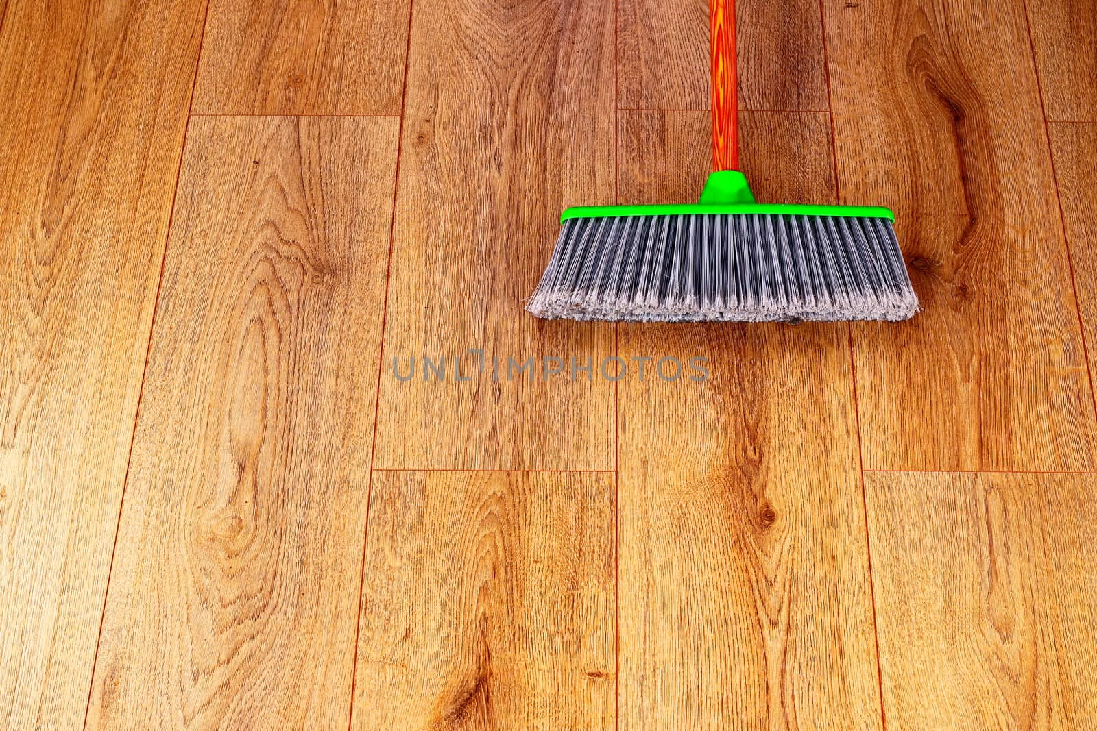 cleaning wooden floor with green plastic broom by taviphoto