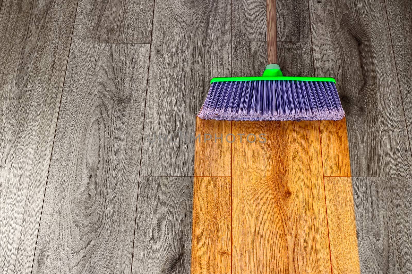 sweeping out wooden parquet with green plastic broom