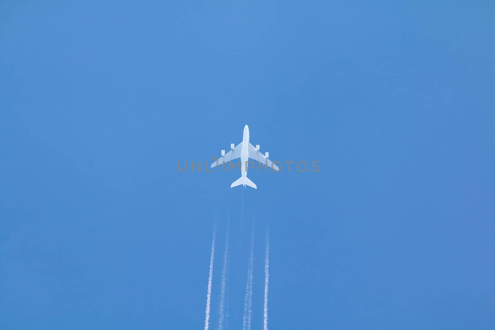 Passenger jet airplane with contrail or vapour trail against clear blue sky.