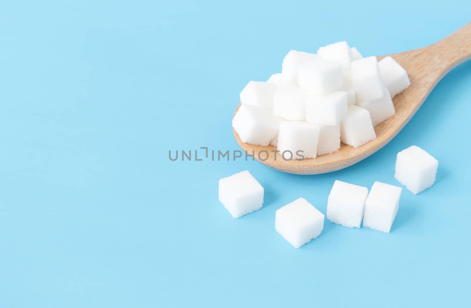 Closeup sugar cubes on wooden spoon white blue background by pt.pongsak@gmail.com