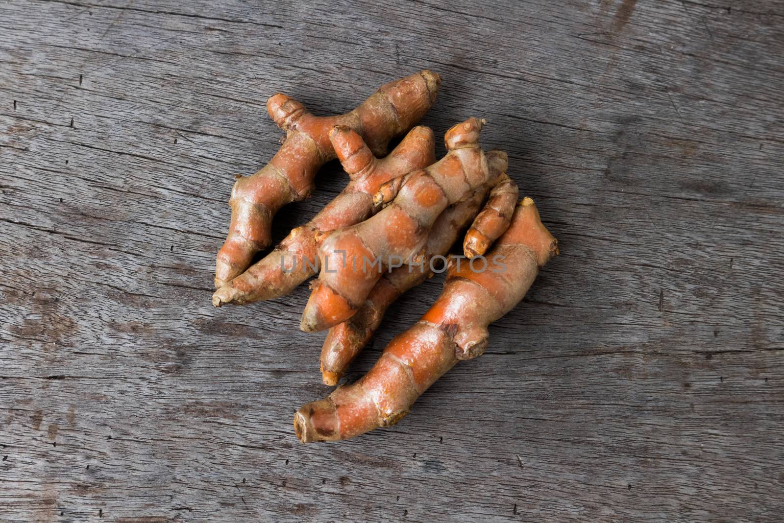 Fresh turmeric roots on wood background, herb and healthy care c by pt.pongsak@gmail.com