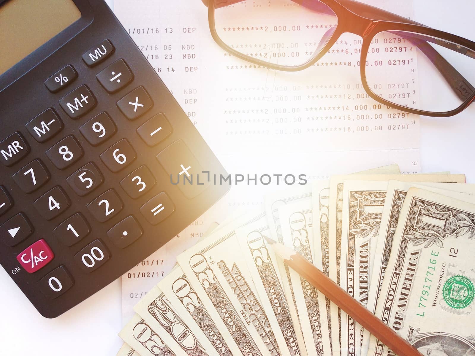 Business, finance, savings, banking or loan concept : Pencil, calculator, money, eyeglasses and savings account passbook or financial statement on white background