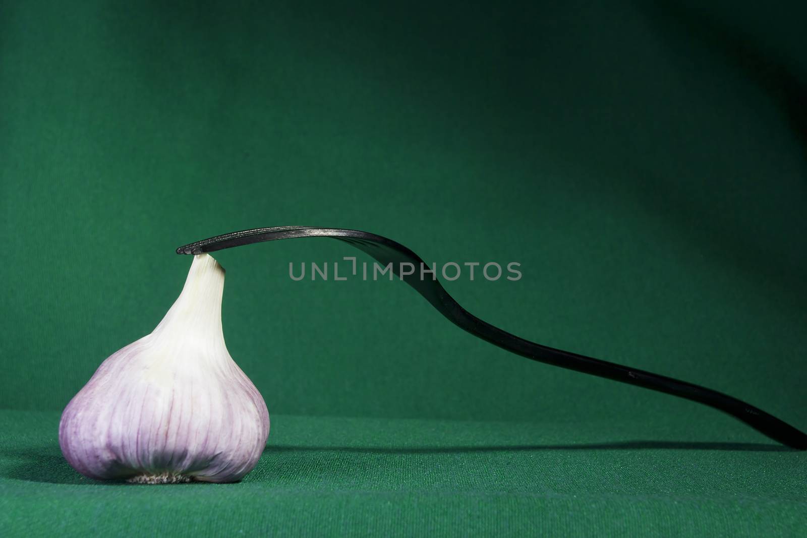 Fork and garlic on a green background