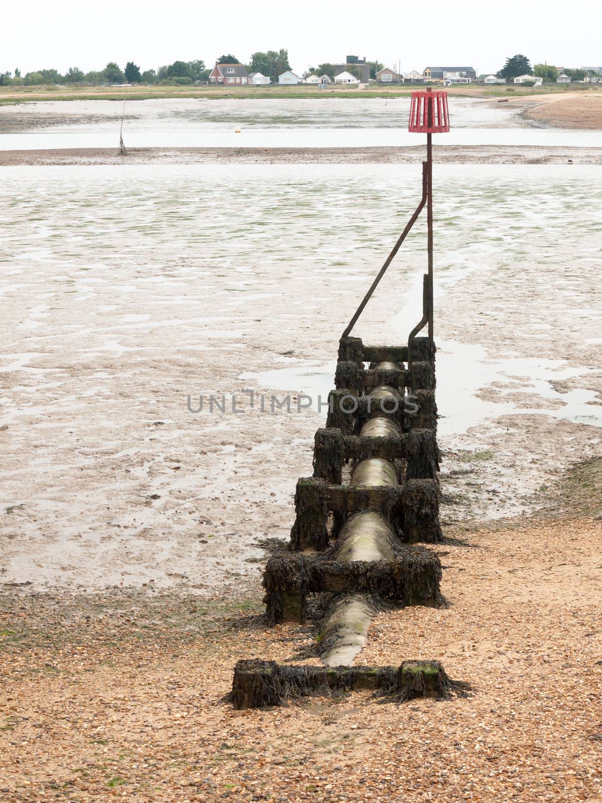 a pipe leading out to sea with sign metal on top groyne; England; UK