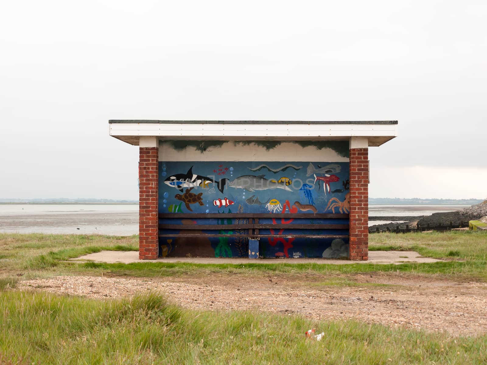 painted public roofed seats at seaside no people; England; UK
