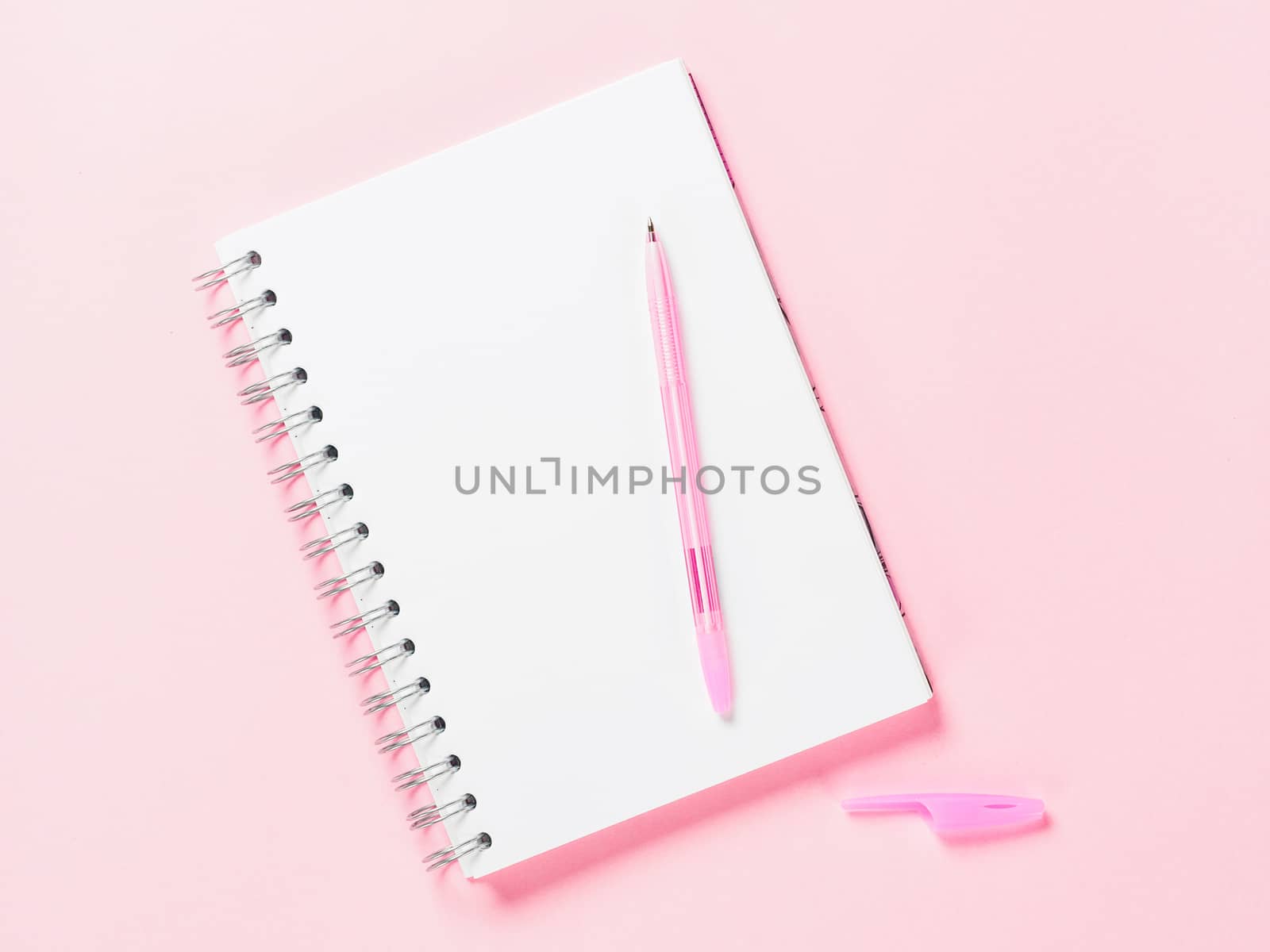 Top view of blank note paper with pen on pink pastel background. Copy space. Back to school and education concept
