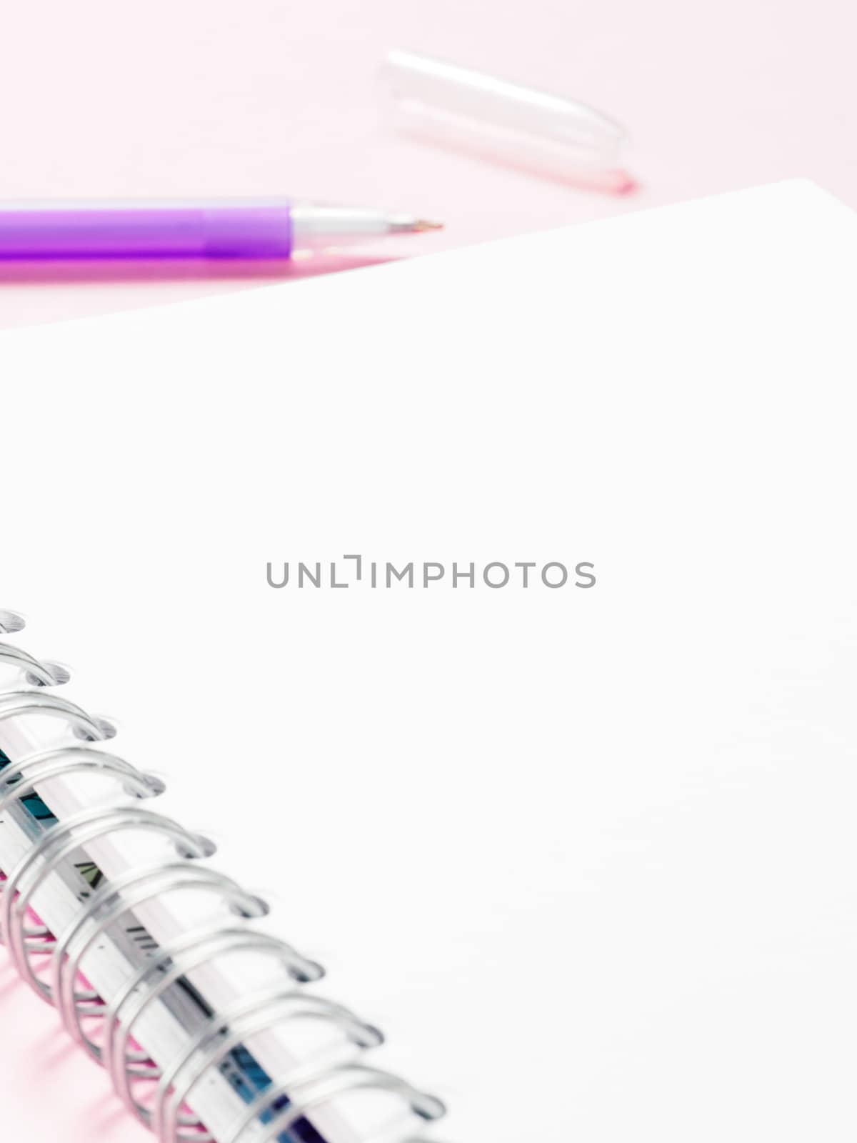 Close up view of blank note paper with pen on pink pastel background. Copy space. Back to school and education concept. Selective focus. Shallow DOF