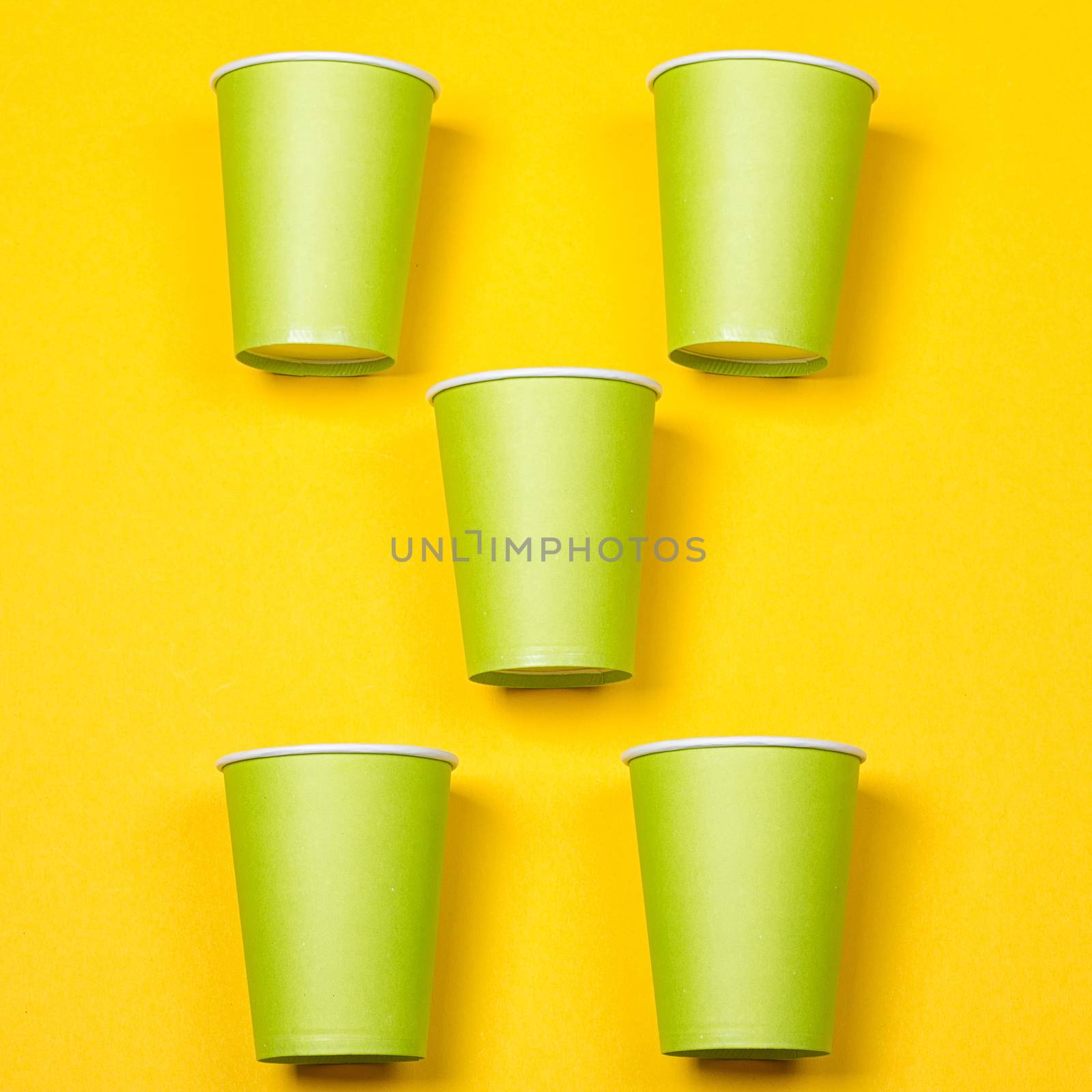 Set of green paper cups on a yellow background