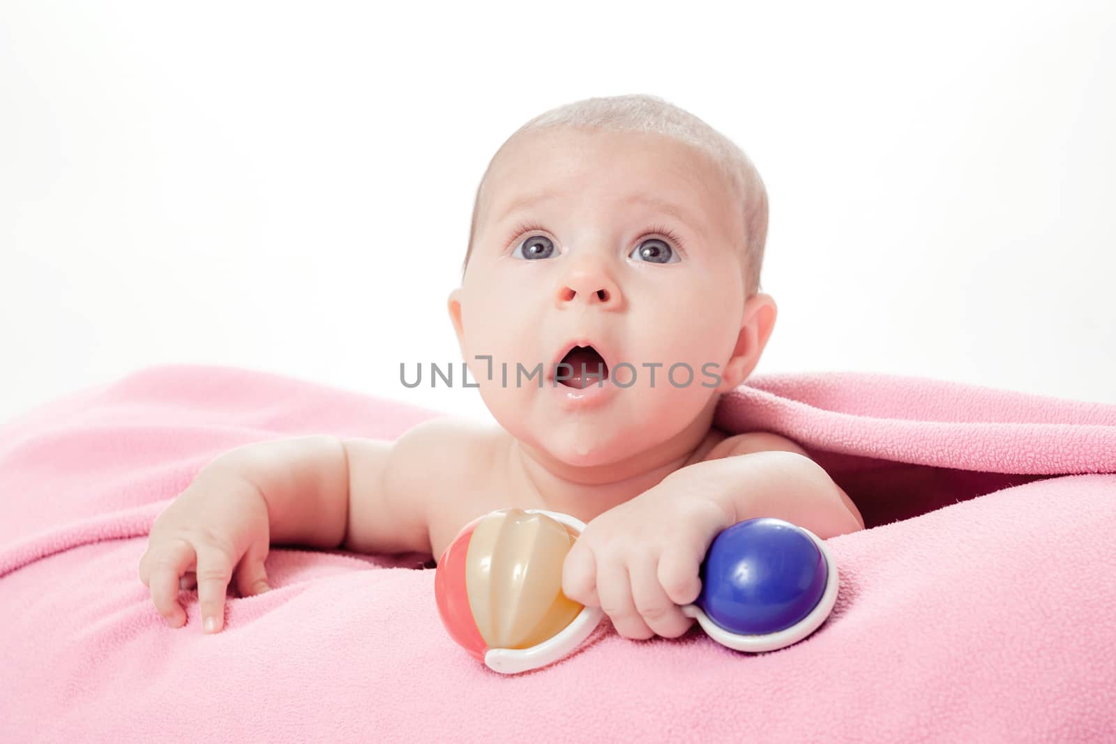 the little beautiful baby under a pink plaid with a rattle in a hand