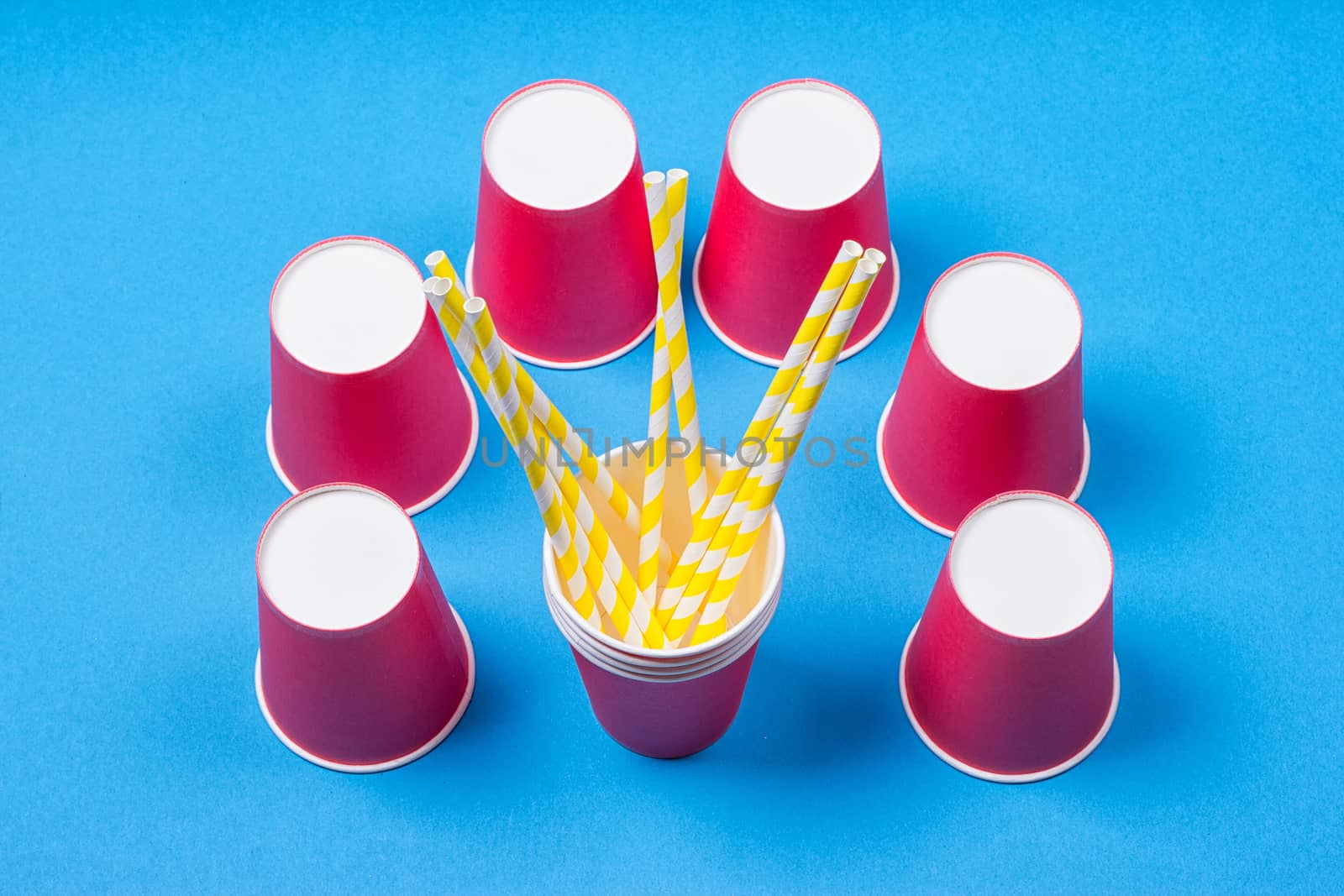 a bundle of multi-colored drinking straws in a paper Cup on a blue background. fashion minimal. flat lay