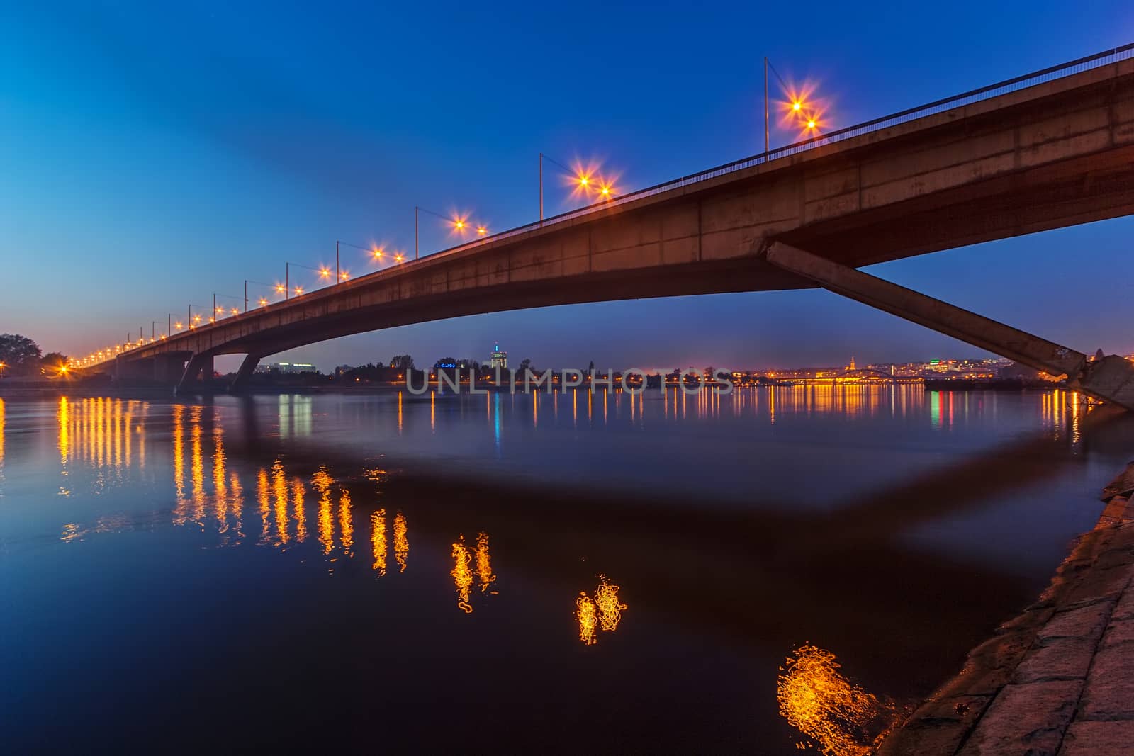 Bridge across river at night by vladimirnenezic