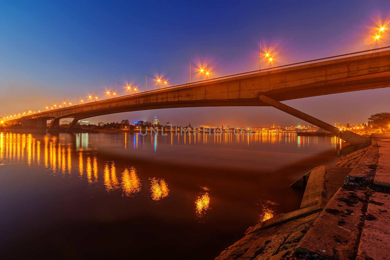 Bridge across river at night by vladimirnenezic