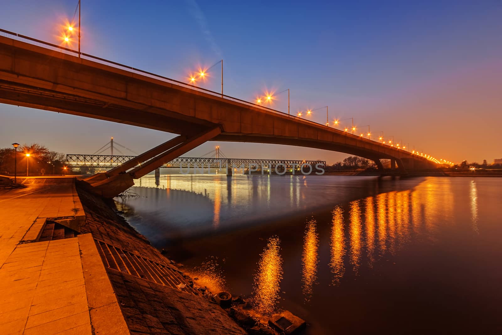 Steel bridge across river at night with artificial lightning