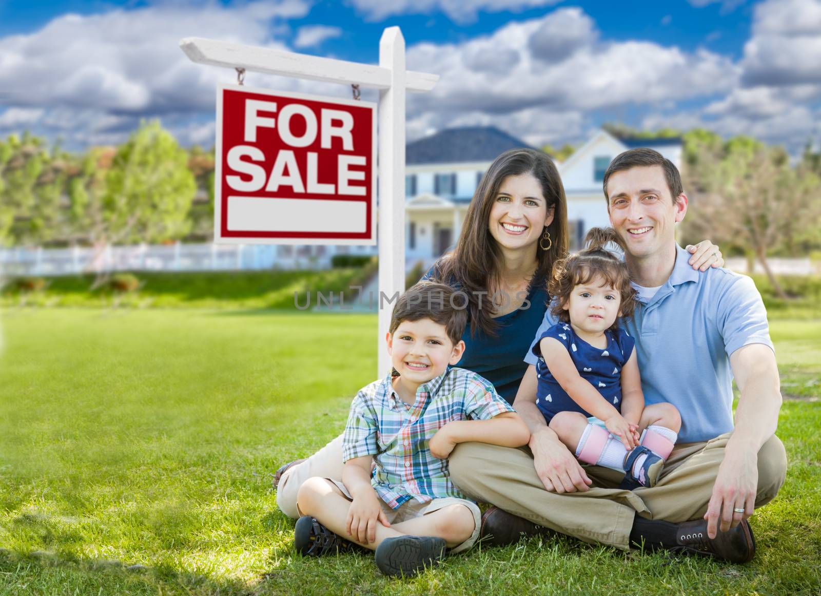 Young Family With Children In Front of Custom Home and For Sale Real Estate Sign. by Feverpitched