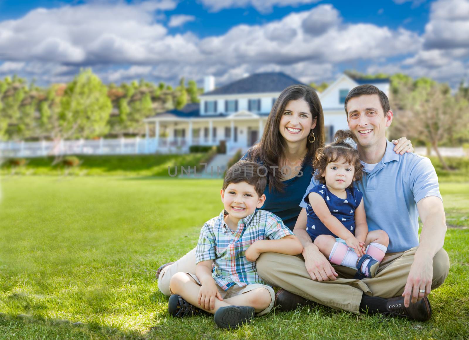 Happy Young Family With Children Outdoors In Front of Beautiful Custom Home. by Feverpitched