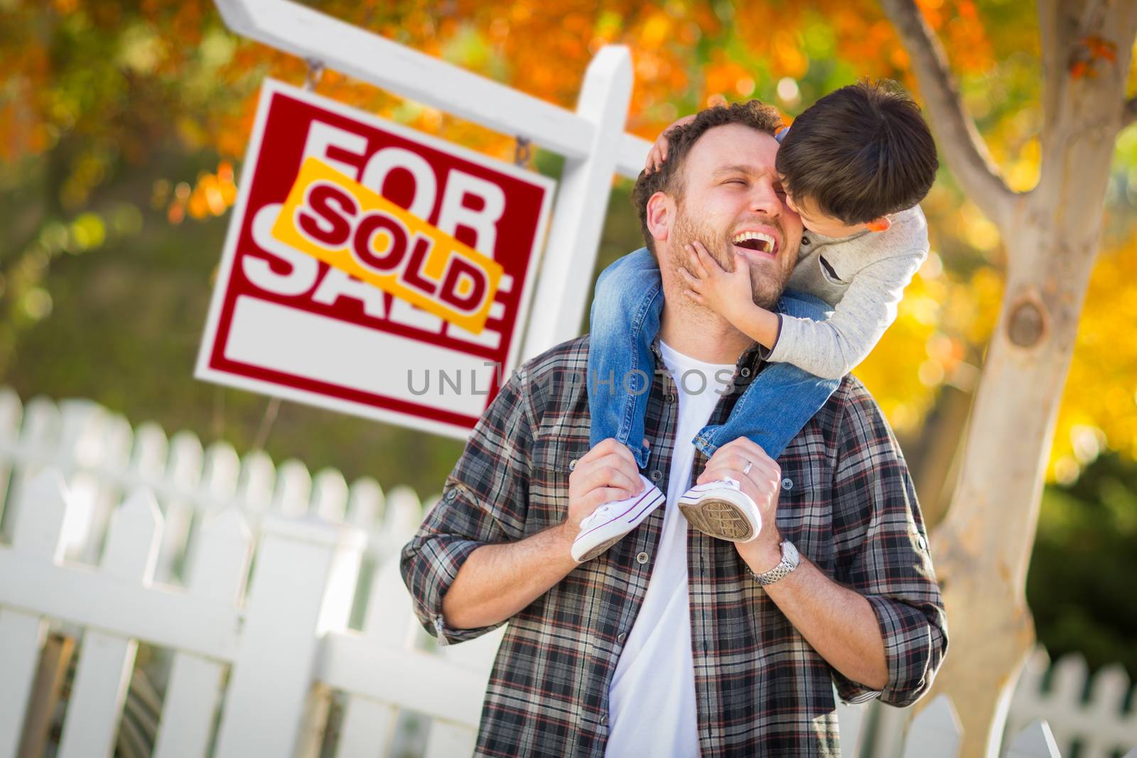 Young Mixed Race Chinese and Caucasian Father and Son In Front of Sold For Sale Real Estate Sign and Fall Yard.