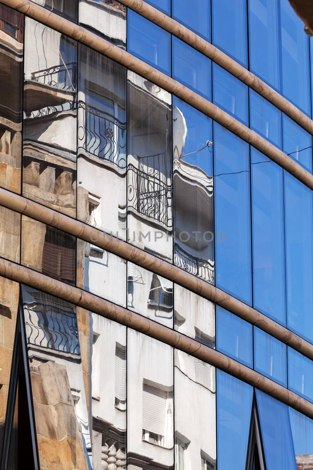 reflection of stone facade on modern glass facade