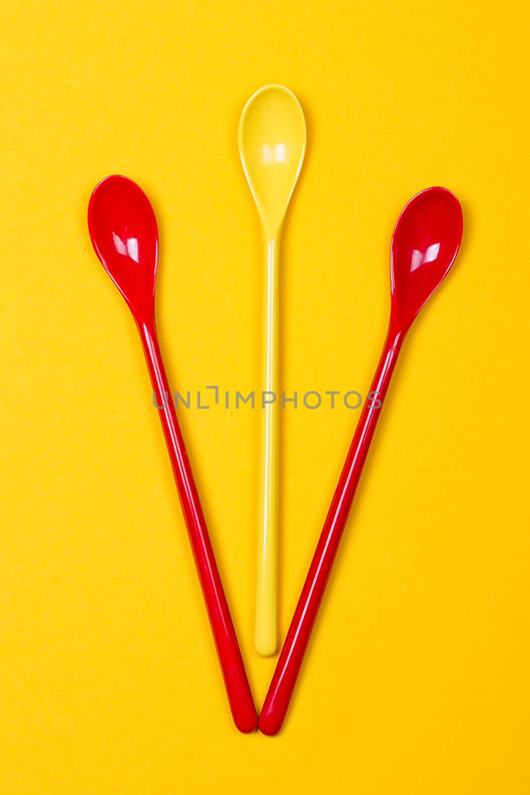 Set of multi-colored long spoons on a yellow background