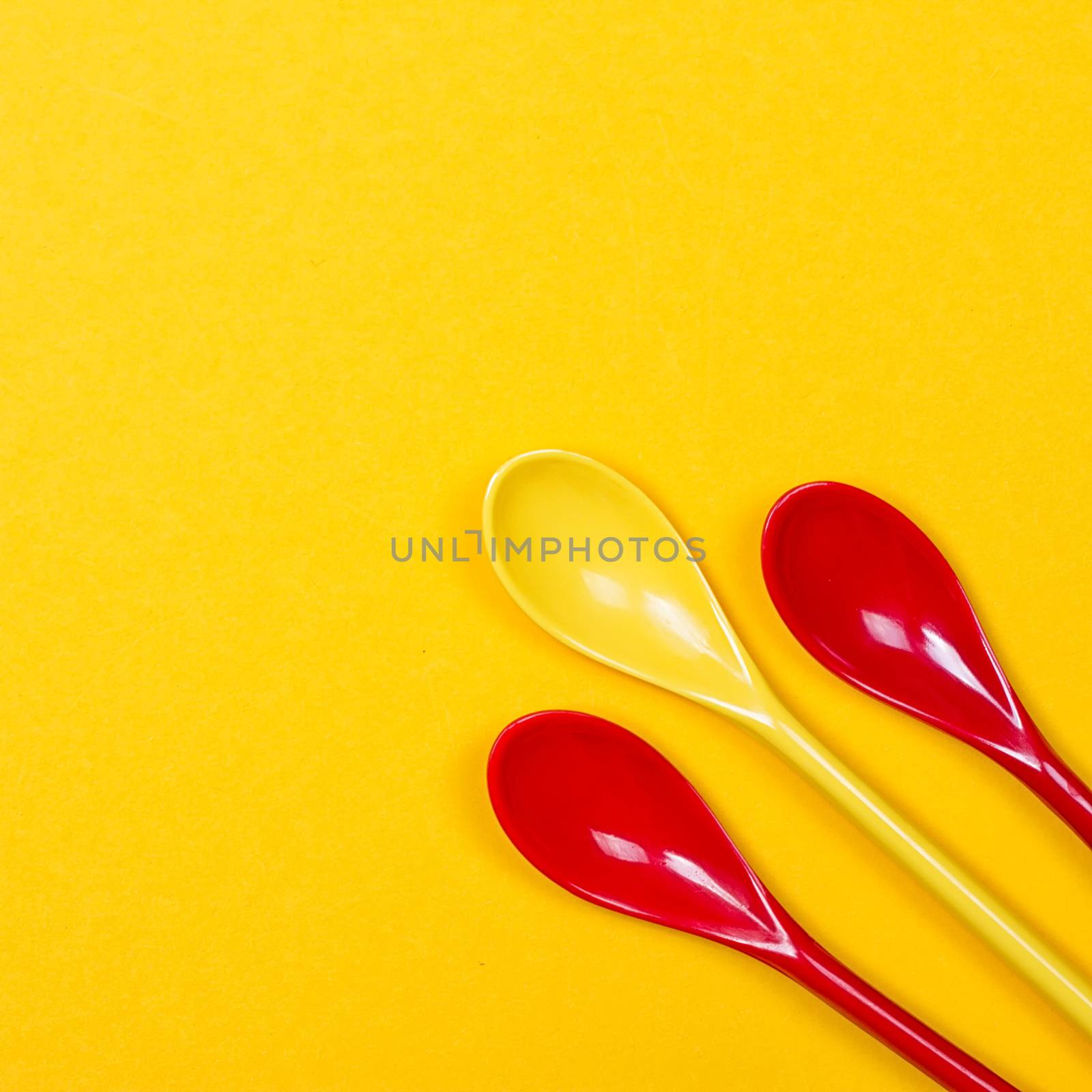 Set of multi-colored long spoons on a yellow background