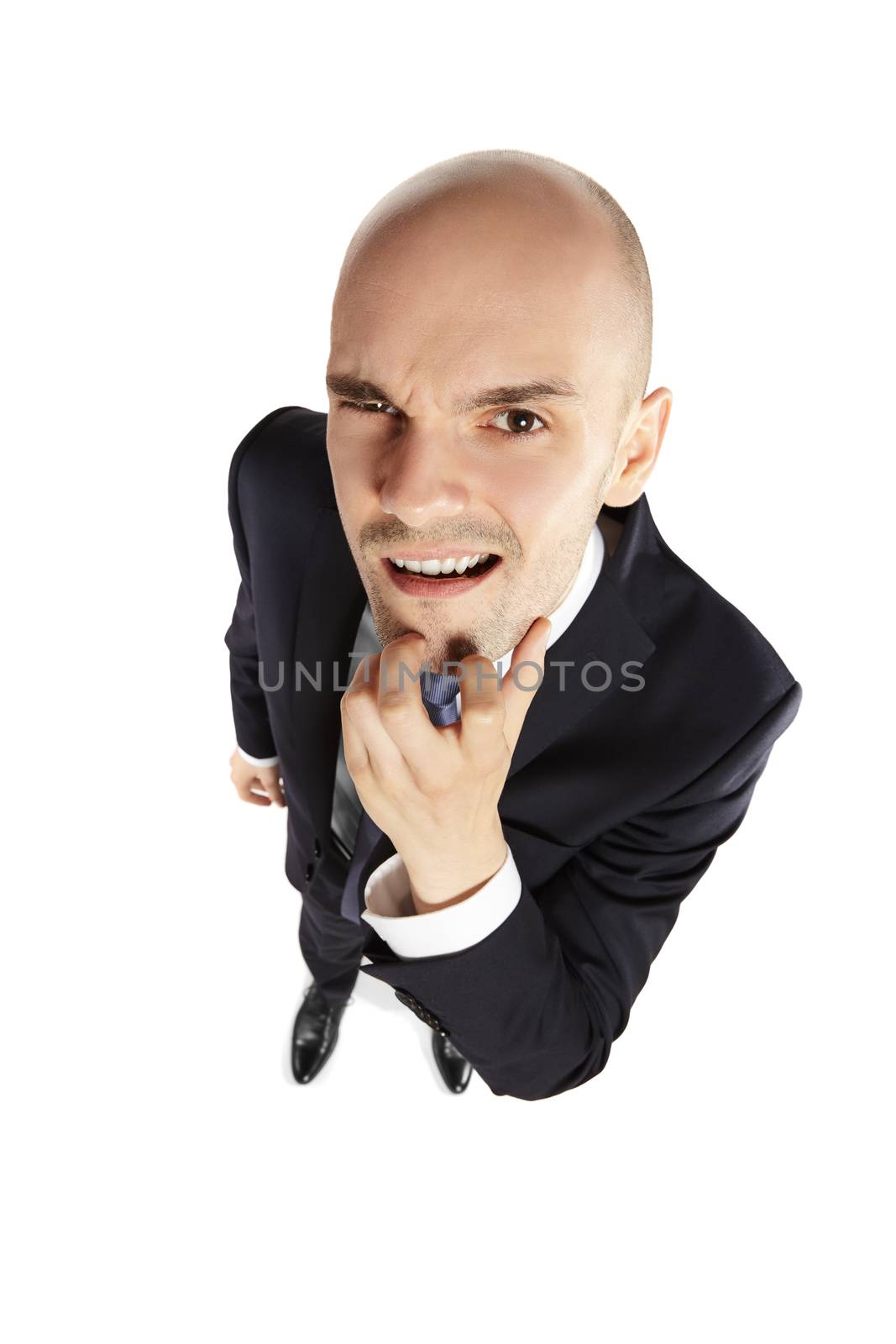 Young businessman scratches his chin and looks at the lens. Above view.