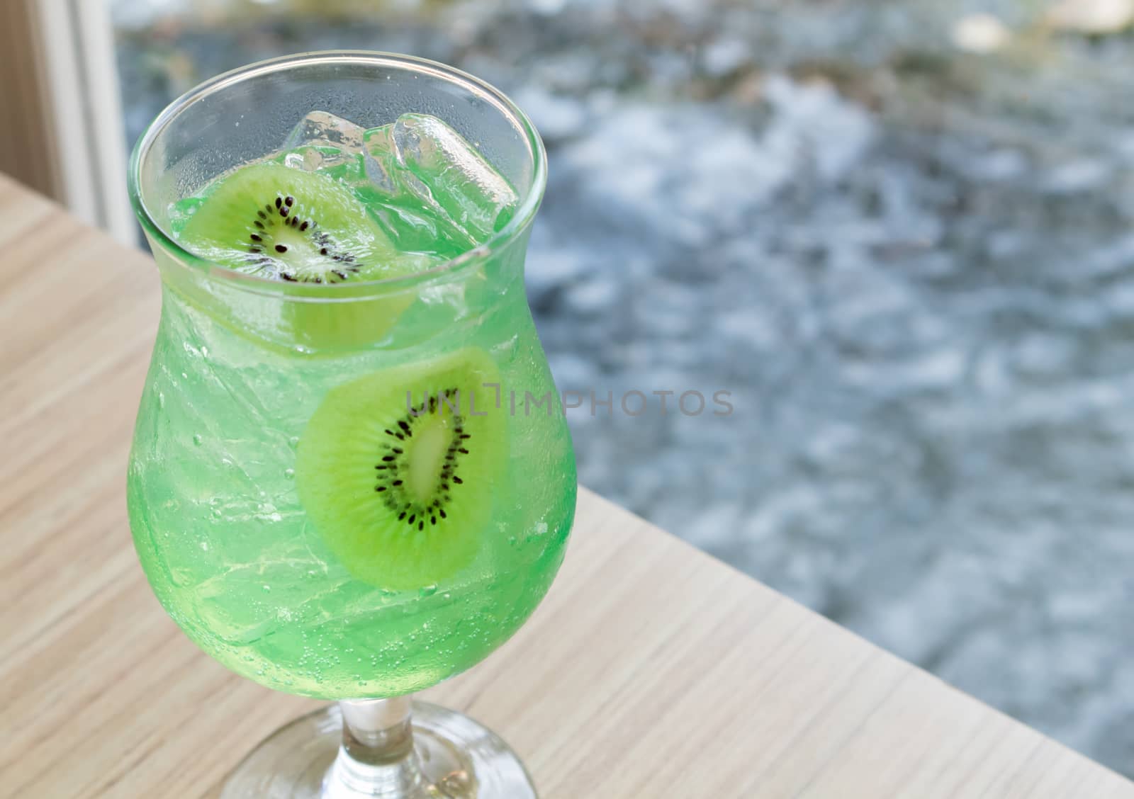 Closeup glass of kiwi soda on wood table, selective focus