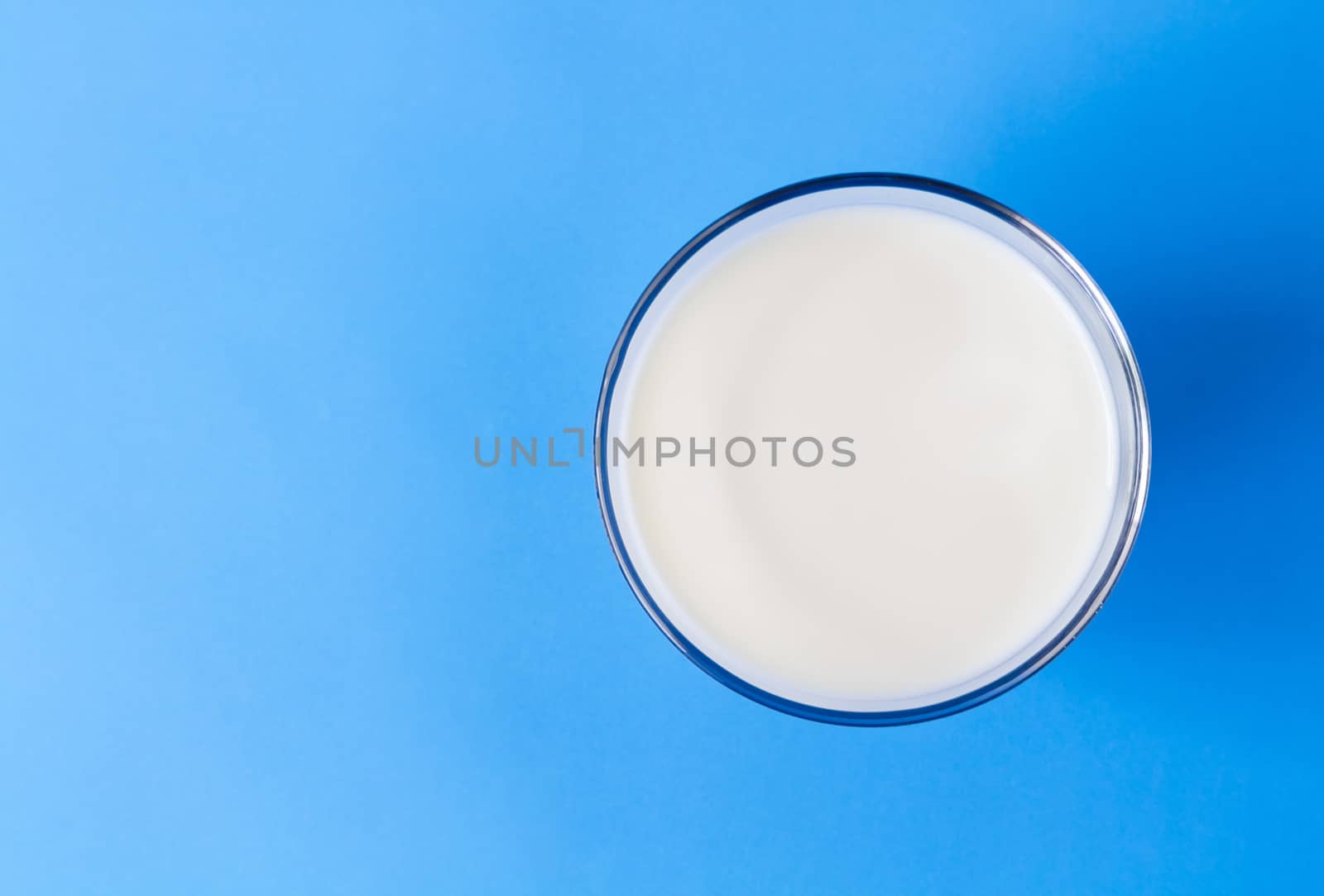 Closeup top view milk glass on blue background, healthy food concept