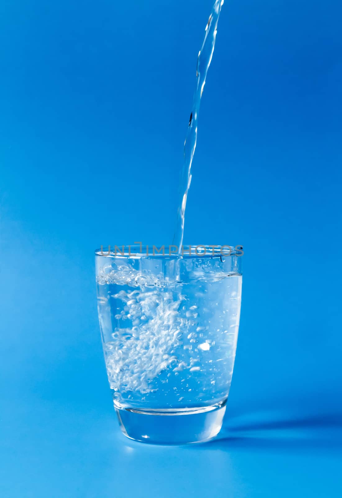 Pouring water into glass on blue background by pt.pongsak@gmail.com