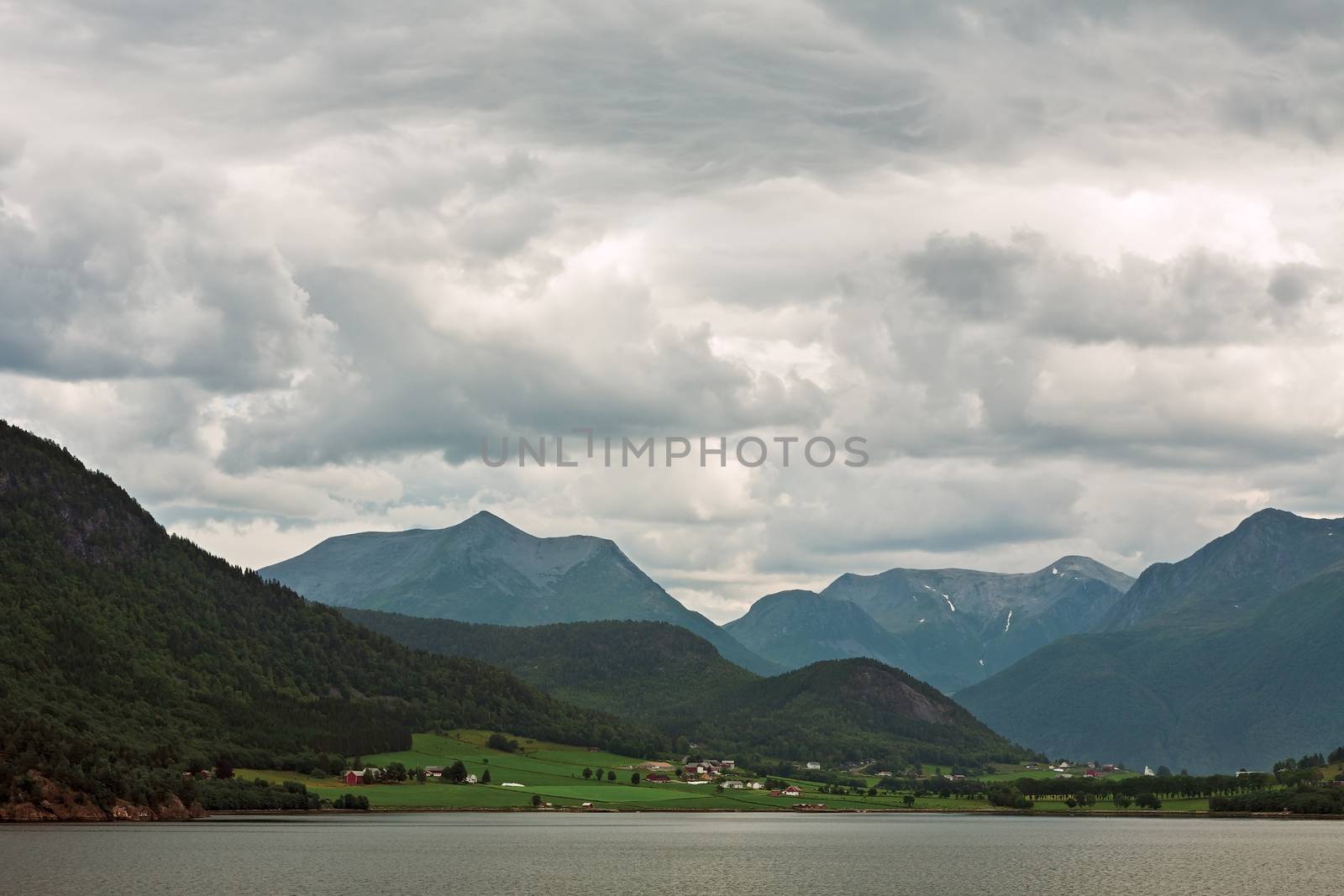 Little village and mountains along the Romsdalsfjorden near Andalsnes under a cloudy sky, Norway