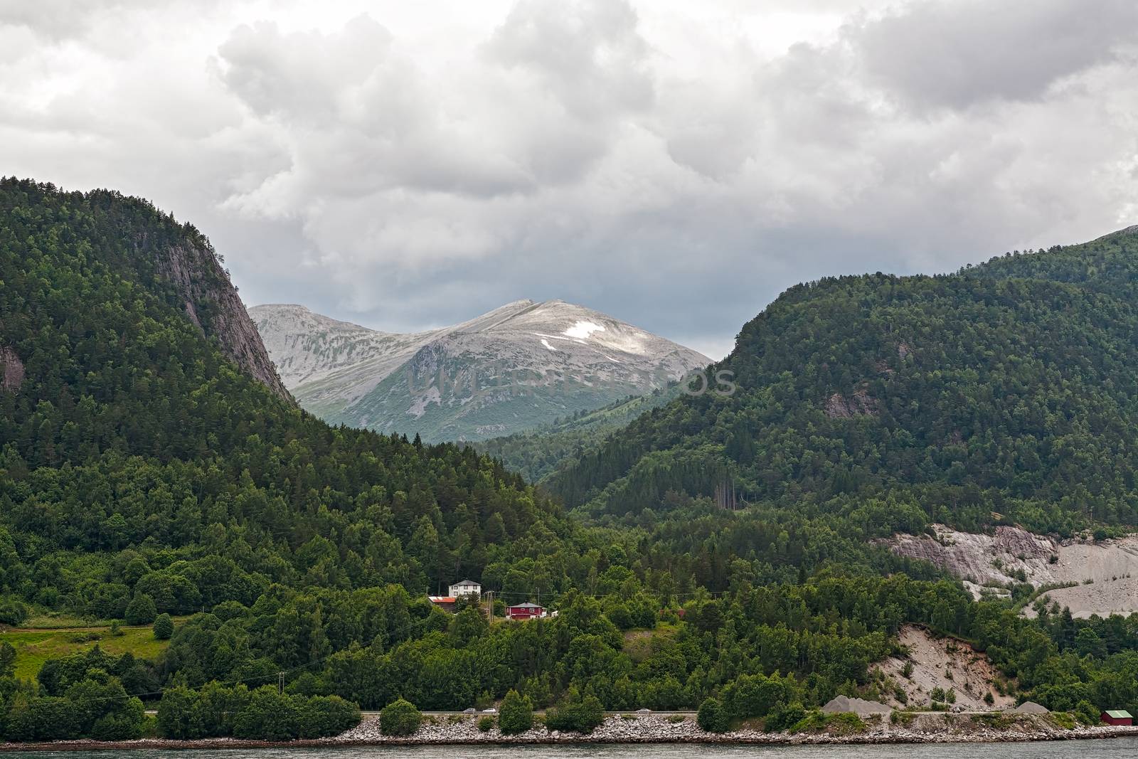 Small houses in the mountains along the Romsdalsfjorden near Andalsnes under a cloudy sky, Norway