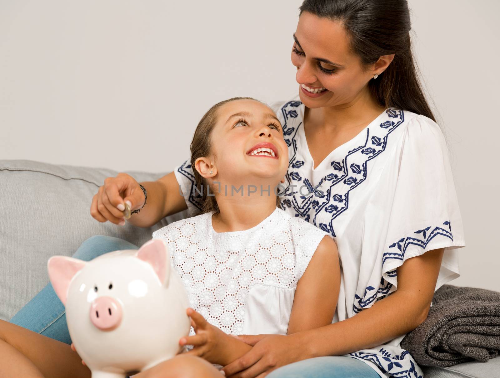 Mother and daughter putting coins into a piggy bank