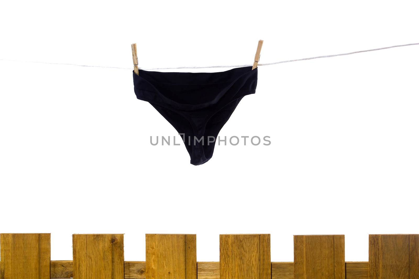 Female underwear dries on a rope behind a fence