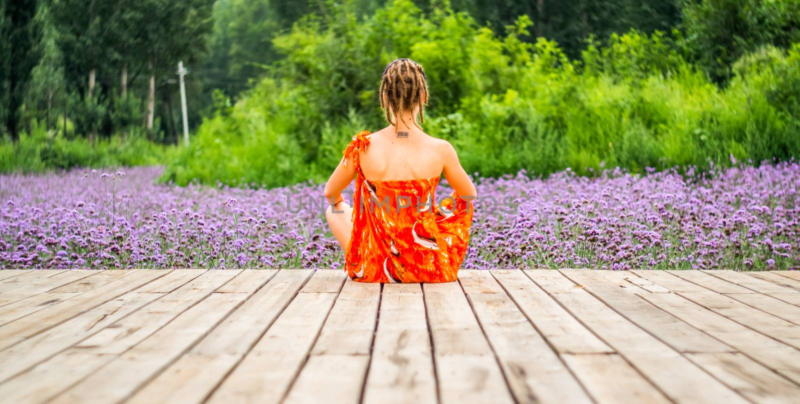 a woman with dreadlocks is sitting on a wooden pier with flowers by Desperada