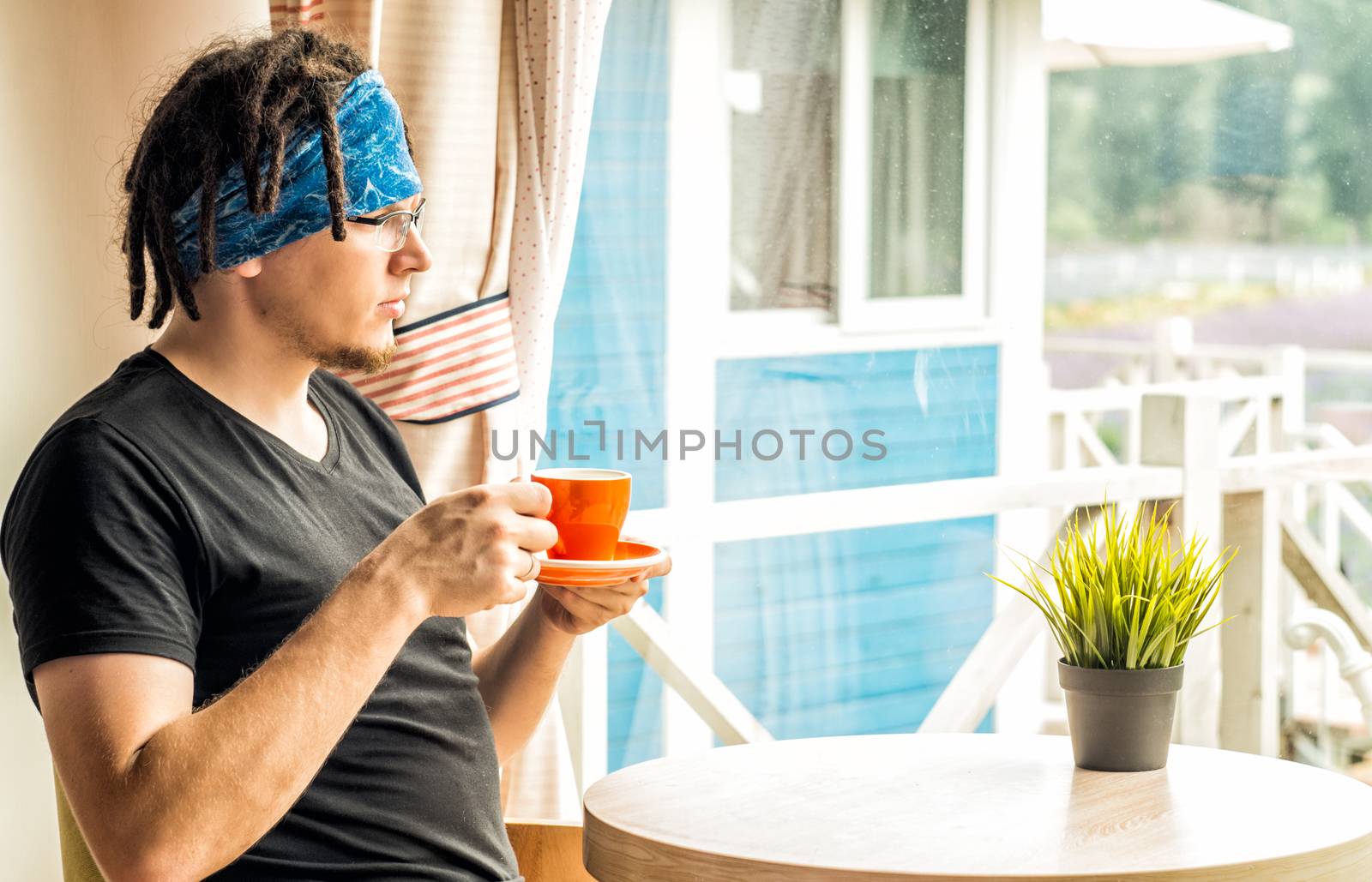 a man with dreadlocks is drinking tea looking to the window