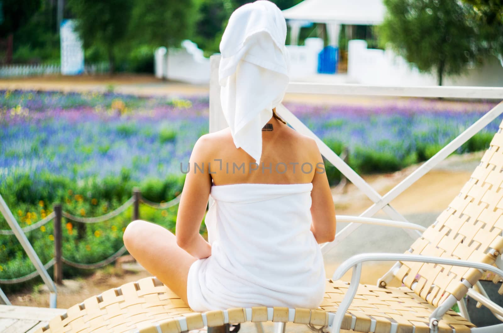 a woman in a bath towel is sitting on a lounge on a terrace looking forward