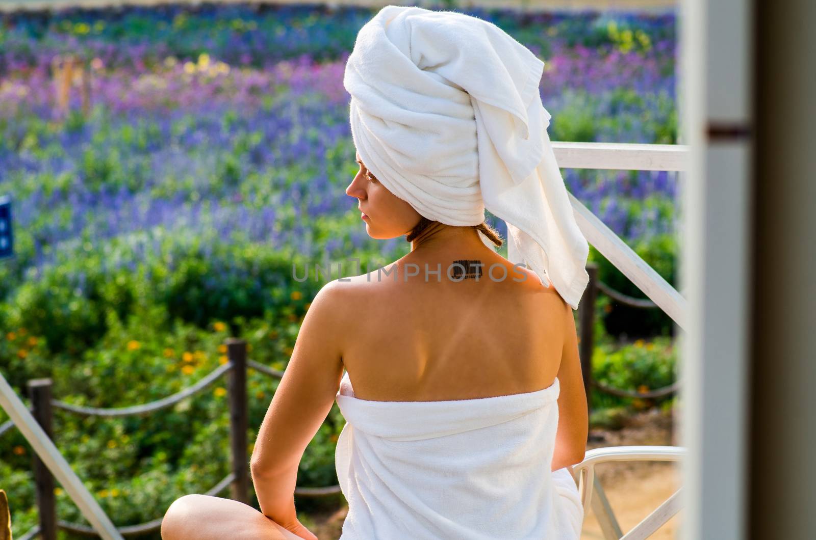 a woman in a bath towel is sitting on a lounge on a terrace