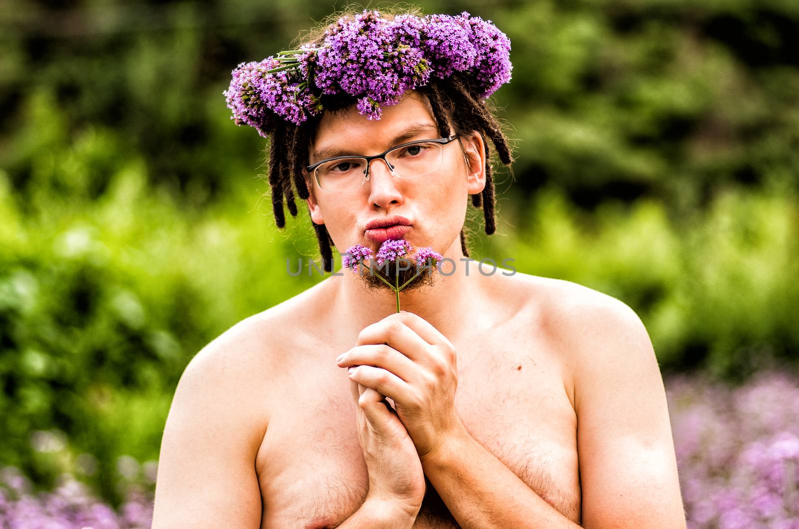 a funny man with dreadlocks and flower wreath holds a flower