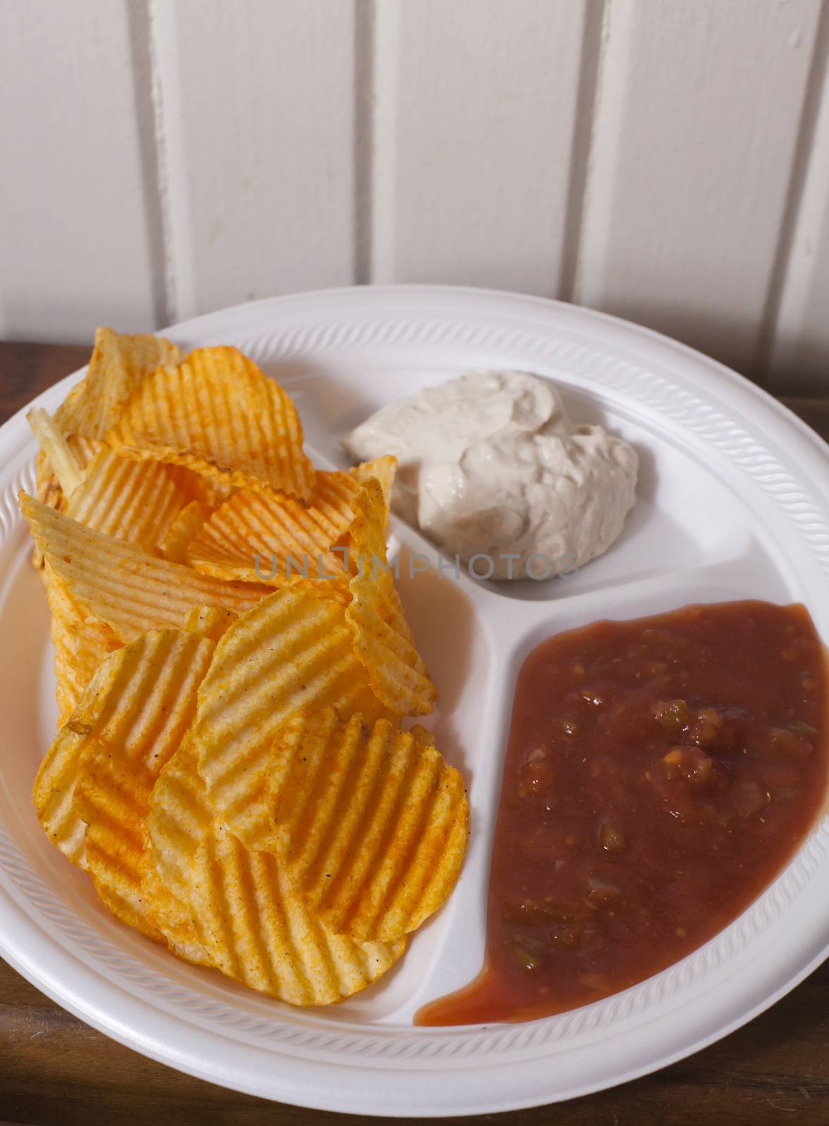 Plate of flavored potato chips with salsa and onion dip